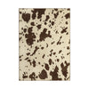 A rectangular area rug with a cow-print pattern featuring dark brown irregular spots on a warm cream background, shown flat against a white background.
